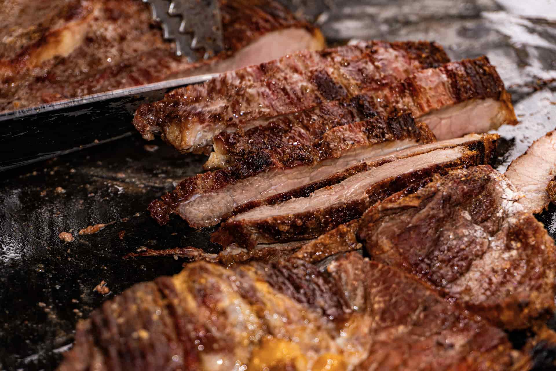 A sliced smoked brisket showing a dark bark and pink smoke ring